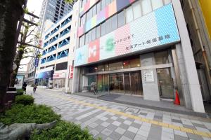 un edificio en una calle con gente caminando delante de él en Culinary Bed&Art 401, en Hamamatsu