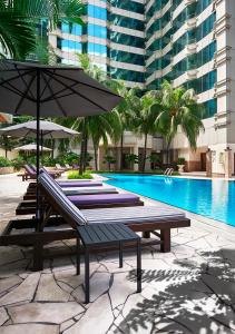 a patio area with a pool, chairs, and a bench at Pullman Kuala Lumpur City Centre Hotel & Residences in Kuala Lumpur