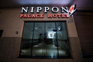 een toegang tot een hotel met een neonbord bij Nippon Palace Hotel in Aparecida