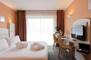 a hotel room with a bed and a desk and a television at Best Western Astoria in Juan-les-Pins