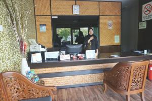 a woman standing at the counter of a restaurant at 1 Baron Motel in Kuah