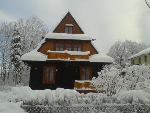 ein schneebedecktes Haus vor einem Zaun in der Unterkunft Willa Dewajtis in Zakopane