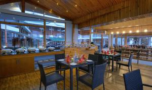 a restaurant with tables and chairs and a bar at TreeHouse Chail Villas in Chail