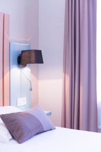 a bedroom with a bed with a lamp and a curtain at Hotel Des Arts in Rueil-Malmaison +30 photos