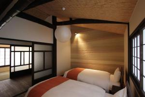 1 dormitorio con 2 camas y 2 ventanas en Anzu an Machiya House, en Kioto