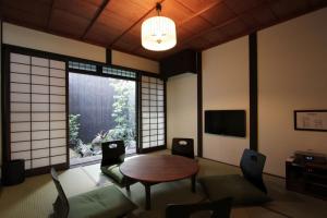 sala de estar con mesa, sillas y ventana en Anzu an Machiya House, en Kioto