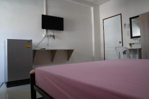 a bedroom with a pink bed and a tv at SKF Apartment in Sakon Nakhon