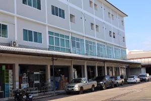 un gran edificio blanco con coches estacionados frente a él en SKF Apartment en Sakon Nakhon