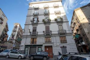 een hoog wit gebouw met auto's geparkeerd voor het bij Agorà Mura Greche B&b in Napels