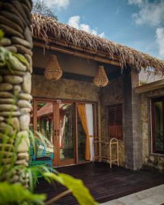a house with a patio and a thatch roof at Bali Bohemia Huts in Ubud