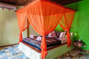 a bedroom with a canopy bed with orange curtains at Bali Bohemia Huts in Ubud