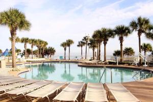 uma piscina com espreguiçadeiras e palmeiras em Ocean Walk Resort 1909 em Daytona Beach