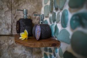 a couple of bottles on a wooden shelf with a flower at Bali Bohemia Huts in Ubud