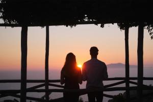 a man and a woman standing in front of a sunset at Hotel Il Girasole in Anacapri