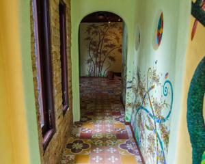 a hallway with a tile floor and a wall with paintings at Bali Bohemia Huts in Ubud