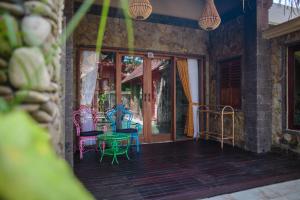 a room with chairs and a table on a porch at Bali Bohemia Huts in Ubud