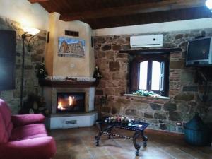 sala de estar con pared de piedra y chimenea en Villaggio dei Balocchi en Castelbuono