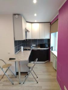 a kitchen with white cabinets and a table and chairs at Sparta Apartments Malmi in Narva