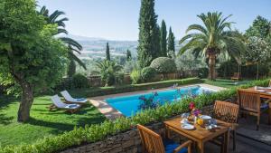 a garden with a table and a swimming pool at Hotel La Fuente de la Higuera in Ronda