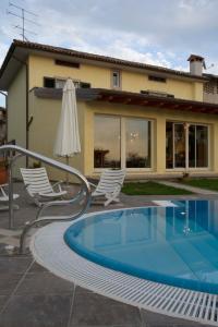 a house with a swimming pool and two chairs and an umbrella at La Casa Sul Fiume in San Daniele del Friuli