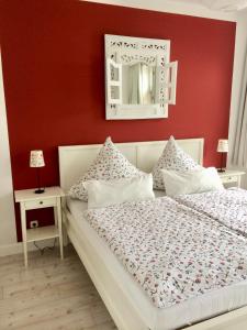 a bedroom with a white bed with a red wall at MÖWE in Ribnitz-Damgarten