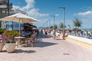 a crowd of people walking down a sidewalk near a beach at Can Miquel (Can Picafort) in Can Picafort