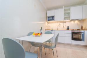 a white kitchen with a white table and chairs at Can Miquel (Can Picafort) in Can Picafort