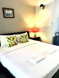 a large white bed in a room with a lamp at The Green Plaza Hotel in Bangrak Beach