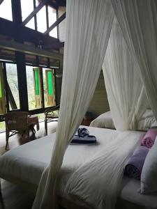 a bedroom with two beds with white drapes at Langit Rimba Resort in Seremban