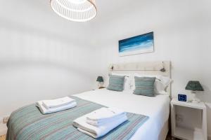 リスボンにあるFLH Alfama Charming Flatの白いベッドルーム(タオル付きのベッド付)