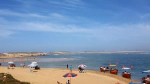 un grupo de personas en una playa con barcos en el agua en Riad7 en Azemmour