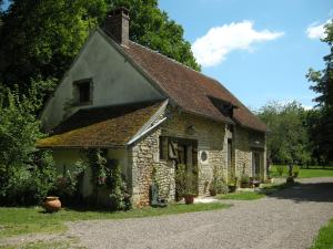 una vieja casa de piedra con flores delante en Les Tramois, en Donzy