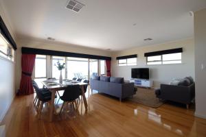 a dining room and living room with a table and chairs at Ochre Point Beach House on Moana Seafront in Moana