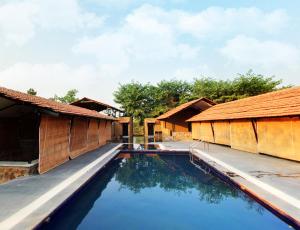 uma vista para uma piscina entre duas cabanas em Maati Jungle Lodge Resort Bandhavgarh em Tāla
