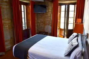 a bedroom with a bed in a room with windows at Hotel Alda Algalia in Santiago de Compostela