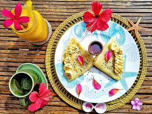 un piatto con cibo e una tazza di caffè e fiori di Coconut Garden Beach Resort a Maumere