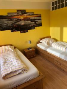 two beds in a room with yellow walls at Julien Felix 1 in Kierspe