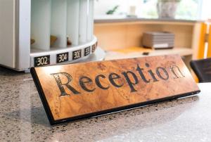 a wooden sign on a counter with the word reception at Hotel Corallo in Gatteo a Mare