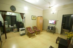 uma sala de estar com duas cadeiras e uma televisão em Shilaj em Dapoli