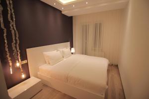 a bedroom with a white bed and a black wall at Superior Apartments in Tbilisi City