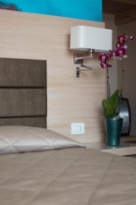 a bedroom with a bed with a lamp and a plant at Alma di Alghero Hotel in Alghero
