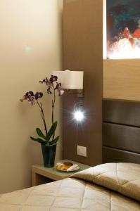 a room with a bed and a table with a vase with flowers at Alma di Alghero Hotel in Alghero