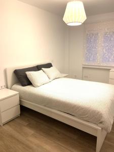 a white bedroom with a white bed with a lamp at Apartamento situado a 10 minutos de opera in Madrid