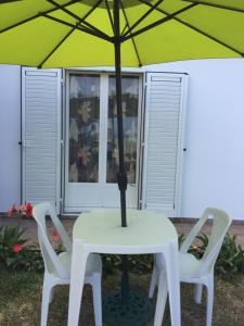 une table et deux chaises avec un parasol dans l'établissement Chambre et pièce confort, à La Possession