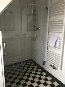 uma casa de banho com uma cabina de duche em vidro e piso em xadrez em Ferienwohnungen Hebbel em Husum