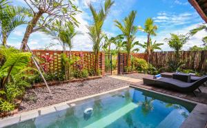 a backyard with a pool and a fence with palm trees at Kampung Canggu in Canggu