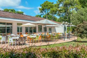 eine Terrasse mit Tischen, Stühlen und Sonnenschirmen in der Unterkunft Azureva Longeville in Longeville-sur-Mer