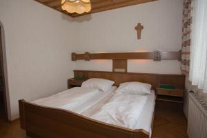 a bedroom with a bed with white sheets and a wooden headboard at Gasthof Maurer in Gloggnitz