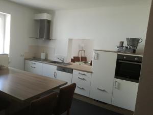 cocina con armarios blancos y mesa de madera en Haus - Anni, en Blieskastel