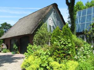 ein Haus mit einem Strohdach vor einem Gebäude in der Unterkunft Nordsee-Paradies in Barlt